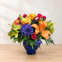 Colorful bouquet of roses, lilies, and chrysanthemums in a blue vase