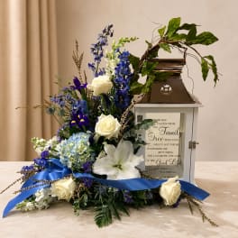 Blue and white floral arrangement with a lantern and ribbon