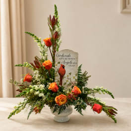 Orange roses in a glass vase with a cardinal memorial sign