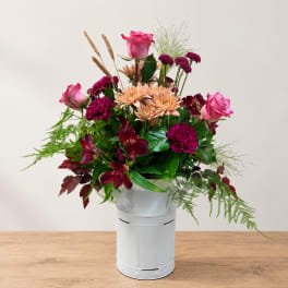 Mixed bouquet in a white metal bucket with pink and burgundy flowers