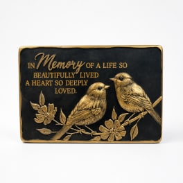 Black memorial plaque with gold birds and flowers