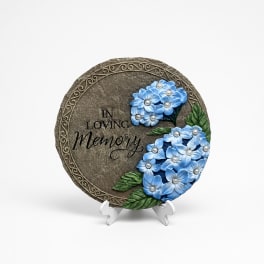 Round memorial plaque with blue flowers and the words In Loving Memory