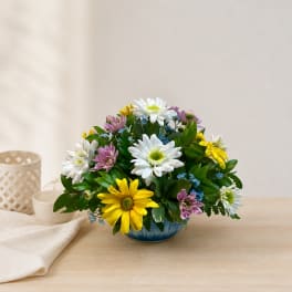 Mixed daisy bouquet in a blue bowl vase on a table