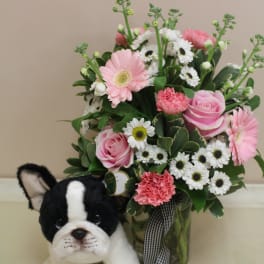 Pink and white flower arrangement with a plush dog in front