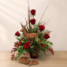 Red roses arranged with pinecones and deer figurines in a vase