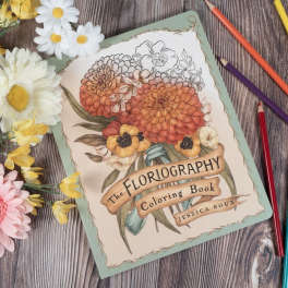 Coloring book with paper flowers and colored pencils on a wood surface
