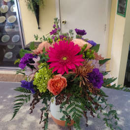 Mixed bouquet in a white vase with bright pink, purple, peach, and green flowers