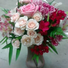 Pink and white rose bouquet in a vase with red accent flowers