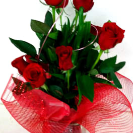 Bouquet of red roses in a clear glass vase with red mesh wrap