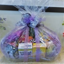 Gift basket wrapped in clear cellophane with snacks and a purple bow