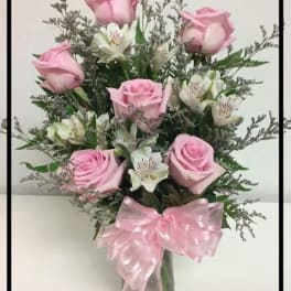 Pink roses and white alstroemeria in a glass vase with a pink bow