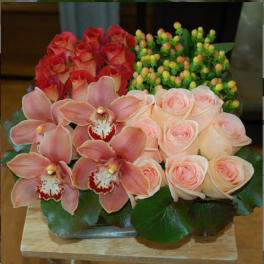 Pink roses and orchids arranged in a low tray