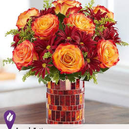 Orange roses and burgundy daisies in a mosaic vase
