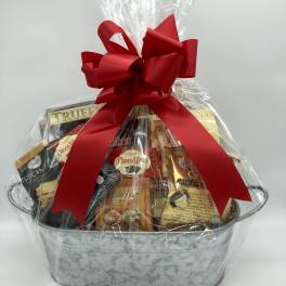 Gift basket of assorted snacks wrapped in clear cellophane with a red bow
