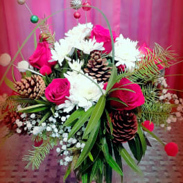 Pink roses and white daisies arranged with pinecones in a decorative basket.