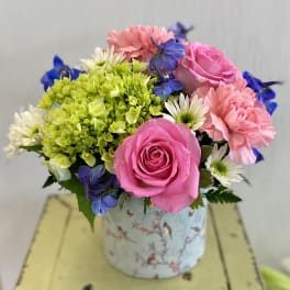 Pink roses, carnations, and daisies in a floral tin container