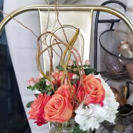Coral roses and white flowers arranged in a clear glass jar