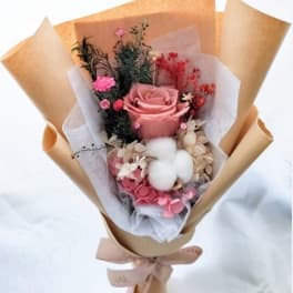 Pink rose bouquet with dried accents and cotton in brown paper