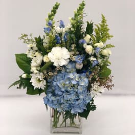 Blue and white floral arrangement in a clear glass vase