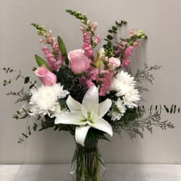 Pink roses, white lilies, and white chrysanthemums in a glass vase