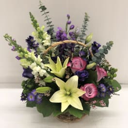 Basket arrangement with pink roses, lilies, and purple flowers