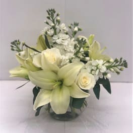 White lilies and roses arranged in a clear glass vase