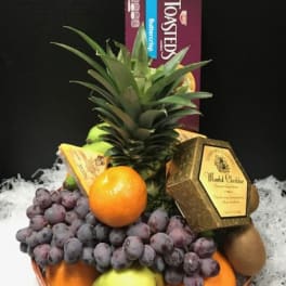 Fruit basket with pineapple, grapes, oranges, pears, and chocolates