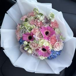 Bouquet of pink and lavender flowers wrapped in white paper
