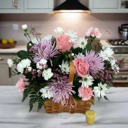 Basket arrangement of pink roses, white daisies, and lavender mums