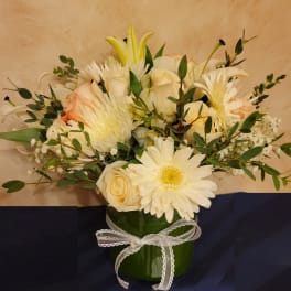 Cream and white bouquet in a green vase with a white ribbon