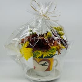 Bouquet of yellow and burgundy flowers in a decorative mug, wrapped in clear cellophane