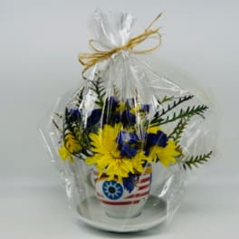 Yellow and blue flowers in a patriotic ceramic pot wrapped in plastic
