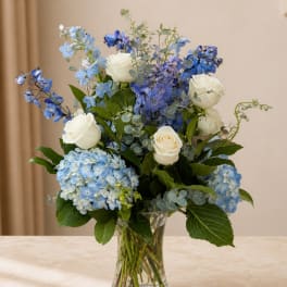 Blue and white flower arrangement in a clear glass vase