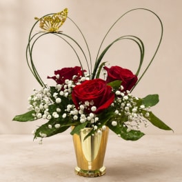 Red roses with baby's breath in a gold vase and butterfly accent