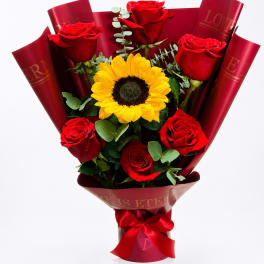 Bouquet of red roses and a yellow sunflower wrapped in red paper