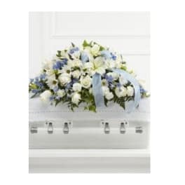 White and blue floral casket spray with a pale blue ribbon