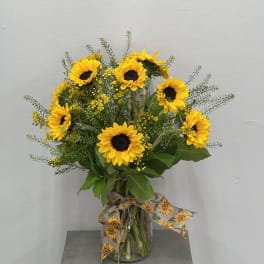Sunflower bouquet in a clear glass vase with a patterned ribbon