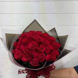 Bouquet of red roses wrapped in black and white paper with a burgundy ribbon