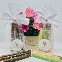 Gift set with pink flowers and decorated pretzel rods in clear bags
