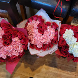 Three bouquets of red roses and pink carnations, one with white hydrangeas