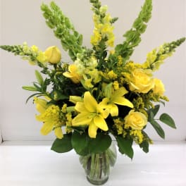 Yellow roses and lilies in a clear glass vase