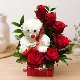 Red roses arranged with a white teddy bear in a red gift box