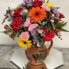 Colorful mixed bouquet in a terracotta vase with a butterfly decoration