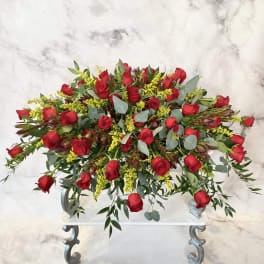 Large arrangement of red roses with yellow filler flowers on a white stand