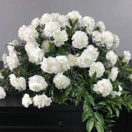 White carnation funeral spray on a dark casket