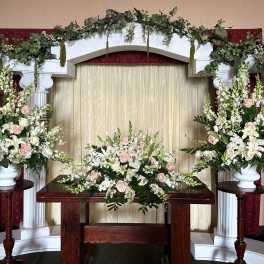 Wedding altar with white and blush floral arrangements on columns and table