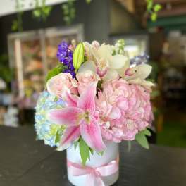 Pink and white floral arrangement in a white hatbox with a pink ribbon