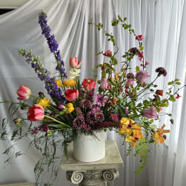 Tall mixed bouquet in a white vase with pink, purple, and yellow flowers
