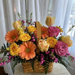 Basket of orange gerberas and yellow, pink, and peach roses