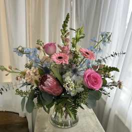 Mixed bouquet in a clear glass vase with pink and blue flowers